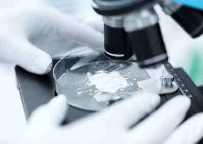 science, chemistry, biology, medicine and people concept - close up of scientist hands with microscope and powder test sample making research in clinical laboratory